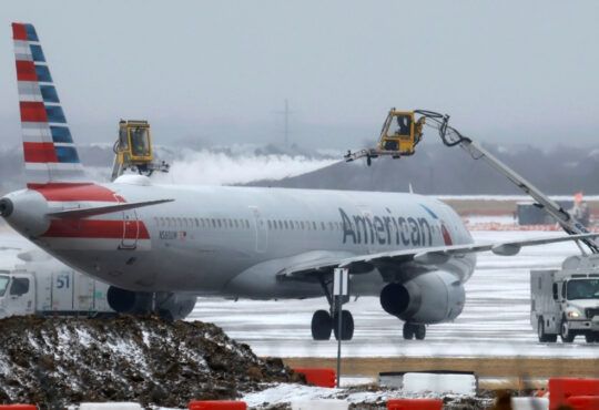 Ground crews de-ice an American Airlines jet at Dallas Fort Worth International Airport during a winter storm in Dallas, Texas
