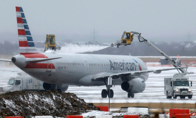 Ground crews de-ice an American Airlines jet at Dallas Fort Worth International Airport during a winter storm in Dallas, Texas