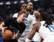 Cooper Flagg of the Dallas Mavericks drives against Ayo Dosunmu and Naz Reid of the Minnesota Timberwolves at American Airlines Center.