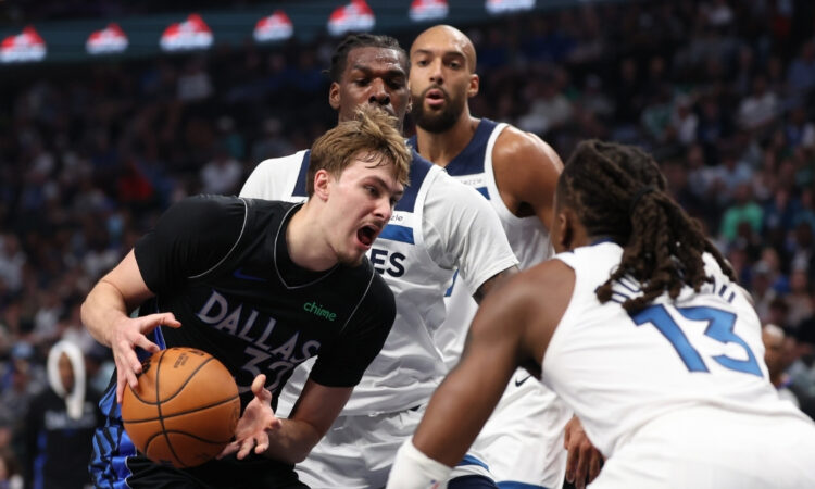 Cooper Flagg of the Dallas Mavericks drives against Ayo Dosunmu and Naz Reid of the Minnesota Timberwolves at American Airlines Center.