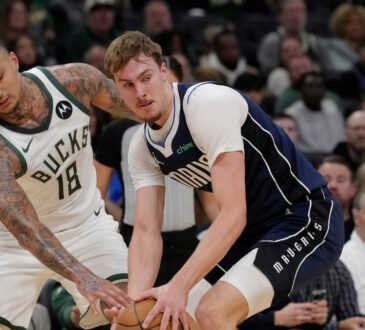 Cooper Flagg #32 of the Dallas Mavericks attempts a steal against Kyle Kuzma #18 of the Milwaukee Bucks during the first quarter at Fiserv Forum.