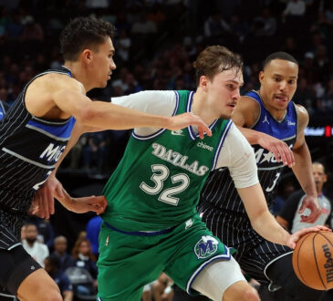 Cooper Flagg #32 of the Dallas Mavericks drives to the basket between Orlando Magic's Tristan da Silva and Desmond Bane during a historic 51-point game at American Airlines Center.