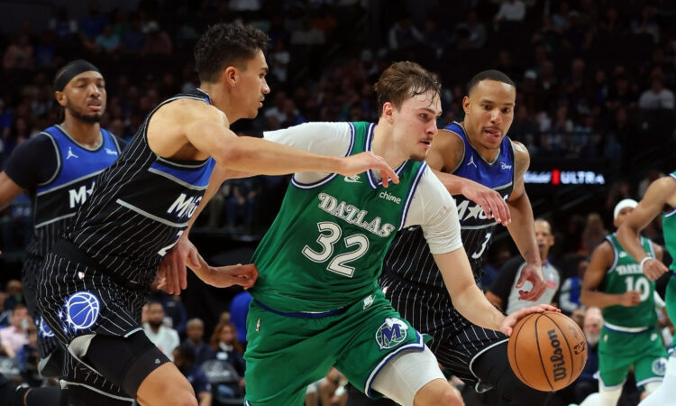 Cooper Flagg #32 of the Dallas Mavericks drives to the basket between Orlando Magic's Tristan da Silva and Desmond Bane during a historic 51-point game at American Airlines Center.