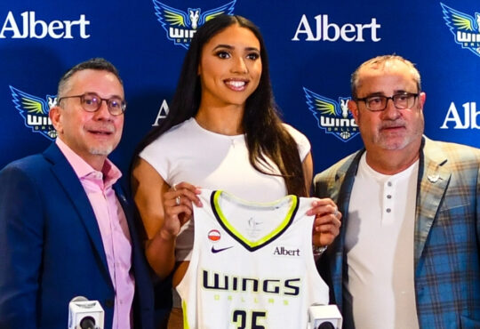 Azzi Fudd holds up her new #35 Dallas Wings jersey alongside General Manager Curt Miller and head coach Jose Fernandez during her introductory press conference in Arlington.