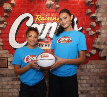 UCLA stars Lauren Betts and Kiki Rice posing with a basketball inside a Raising Cane’s restaurant in Hollywood after winning the 2026 NCAA Championship.