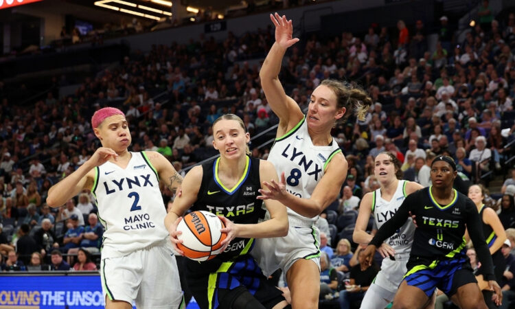 Paige Bueckers of the Dallas Wings drives to the basket against Alanna Smith and Natisha Hiedeman of the Minnesota Lynx.