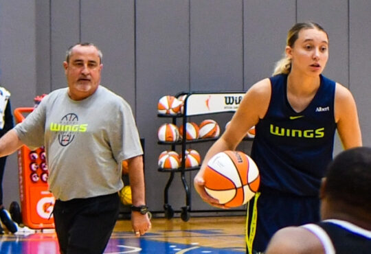 Dallas Wings star Paige Bueckers handles the ball in transition while head coach Jose Fernandez watches from the sideline at College Park Center.