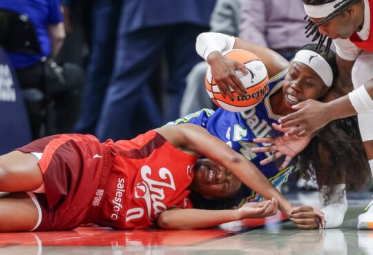 Arike Ogunbowale (24) of the Dallas Wings and Kelsey Mitchell (0) of the Indiana Fever battle for a loose ball at Gainbridge Fieldhouse.