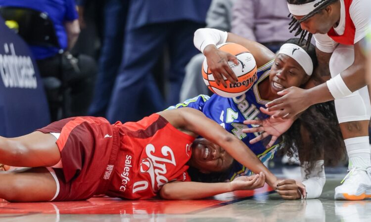Arike Ogunbowale (24) of the Dallas Wings and Kelsey Mitchell (0) of the Indiana Fever battle for a loose ball at Gainbridge Fieldhouse.