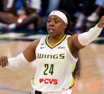 Arike Ogunbowale pointing toward an open teammate along the floor during a game against Minnesota.