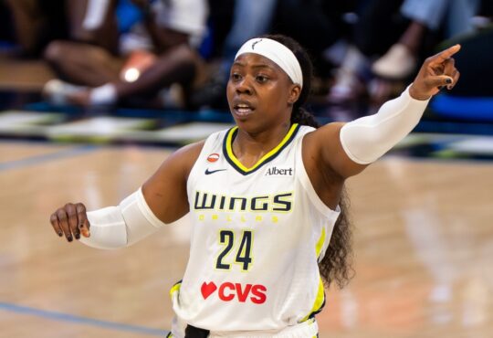 Arike Ogunbowale pointing toward an open teammate along the floor during a game against Minnesota.