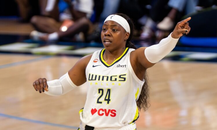 Arike Ogunbowale pointing toward an open teammate along the floor during a game against Minnesota.