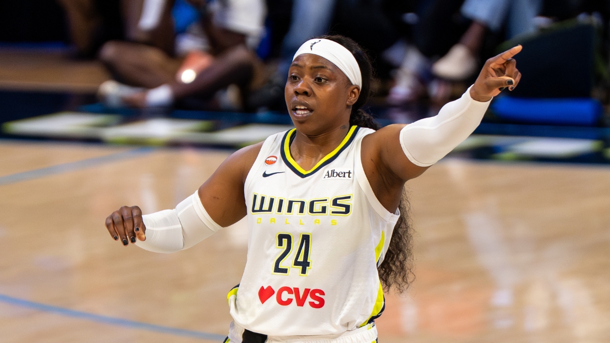 Arike Ogunbowale pointing toward an open teammate along the floor during a game against Minnesota.