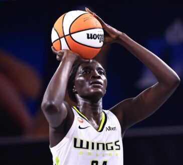 Forward Awak Kuier standing at the free-throw line, focusing on the rim with the ball balanced in her hands before launching her shot attempt.