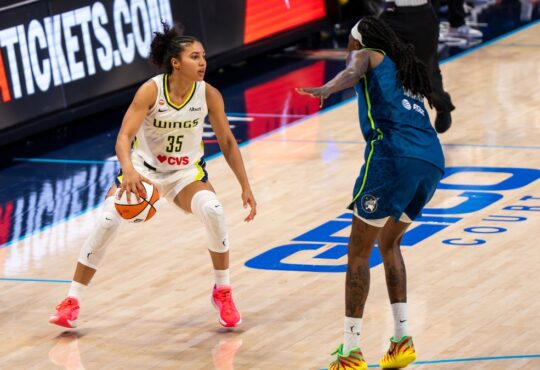 Rookie guard Azzi Fudd of the Dallas Wings handling the ball while being defended by Natasha Howard of the Minnesota Lynx.