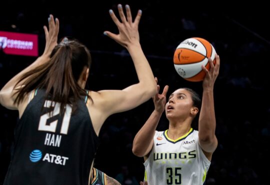 Rookie guard Azzi Fudd releasing a high-arcing jump shot over the contested challenge of center Han Xu.