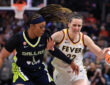 Caitlin Clark of the Indiana Fever brings the ball up the court against defensive pressure from Odyssey Sims of the Dallas Wings at Gainbridge Fieldhouse.