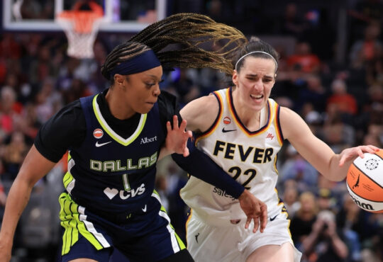 Caitlin Clark of the Indiana Fever brings the ball up the court against defensive pressure from Odyssey Sims of the Dallas Wings at Gainbridge Fieldhouse.
