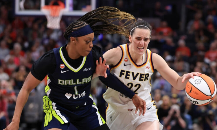 Caitlin Clark of the Indiana Fever brings the ball up the court against defensive pressure from Odyssey Sims of the Dallas Wings at Gainbridge Fieldhouse.
