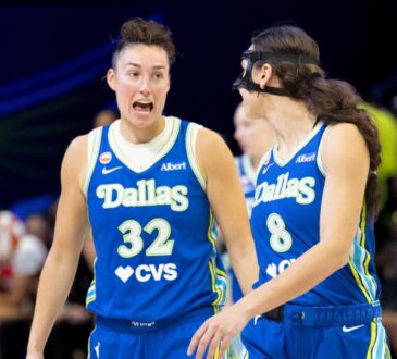 Jessica Shepard and Alanna Smith standing close together on the hardwood, talking and gesturing during a stoppage in play against the Washington Mystics.