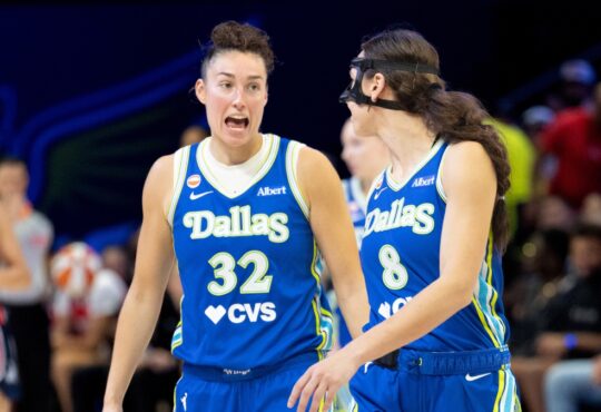 Jessica Shepard and Alanna Smith standing close together on the hardwood, talking and gesturing during a stoppage in play against the Washington Mystics.
