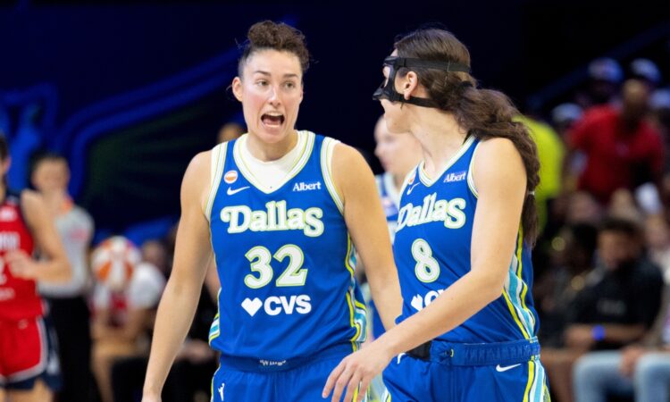 Jessica Shepard and Alanna Smith standing close together on the hardwood, talking and gesturing during a stoppage in play against the Washington Mystics.