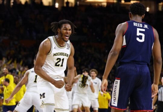 Michigan sophomore big man Morez Johnson Jr. screaming in celebration amidst falling confetti on the court after winning the national title.
