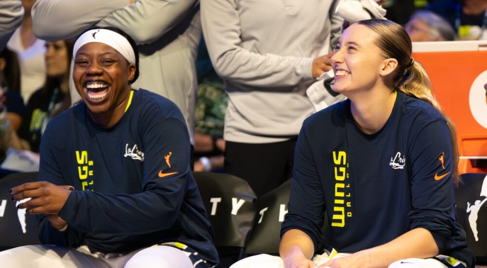 Paige Bueckers and Arike Ogunbowale sitting together on the Dallas Wings bench during the game against the Minnesota Lynx.