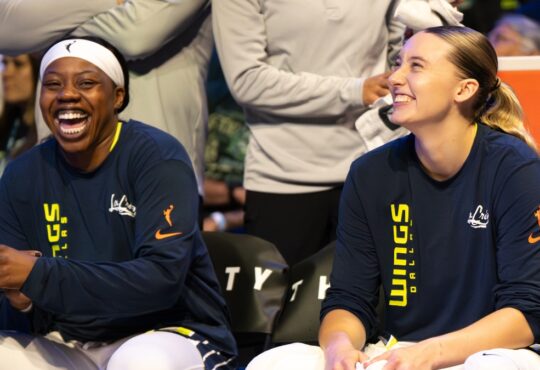 Paige Bueckers and Arike Ogunbowale sitting together on the Dallas Wings bench during the game against the Minnesota Lynx.