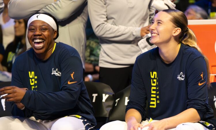 Paige Bueckers and Arike Ogunbowale sitting together on the Dallas Wings bench during the game against the Minnesota Lynx.
