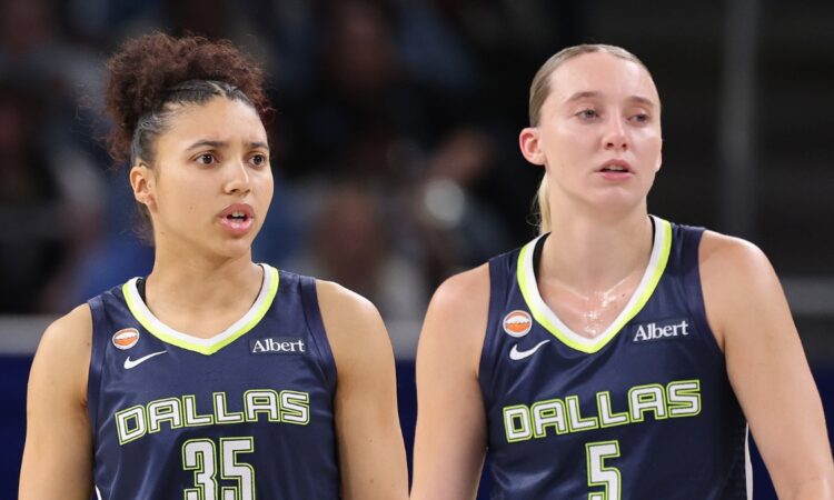 Guard Paige Bueckers and rookie guard Azzi Fudd looking on together from the floor during a game against the Chicago Sky.