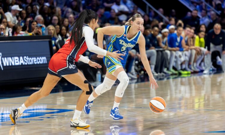 Guard Paige Bueckers of the Dallas Wings dribbling the ball at the perimeter against a Washington Mystics defender at College Park Center.