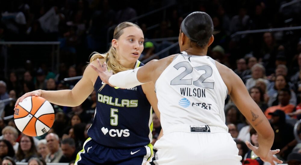 Guard Paige Bueckers driving hard downhill against the perimeter defense of center A'ja Wilson.
