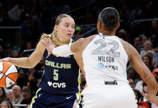 Guard Paige Bueckers driving hard downhill against the perimeter defense of center A'ja Wilson.