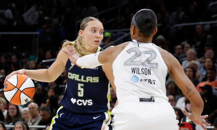 Guard Paige Bueckers driving hard downhill against the perimeter defense of center A'ja Wilson.