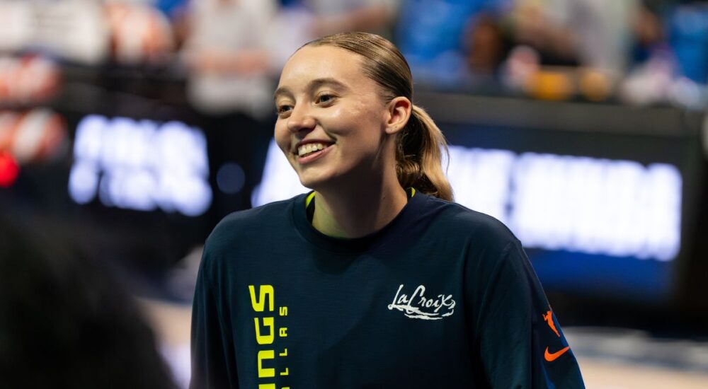 Guard Paige Bueckers wearing a blue Dallas Wings zip-up warmup jacket on the court before a game.