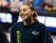 Guard Paige Bueckers wearing a blue Dallas Wings zip-up warmup jacket on the court before a game.