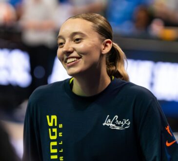 Guard Paige Bueckers wearing a blue Dallas Wings zip-up warmup jacket on the court before a game.