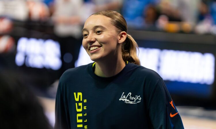 Guard Paige Bueckers wearing a blue Dallas Wings zip-up warmup jacket on the court before a game.