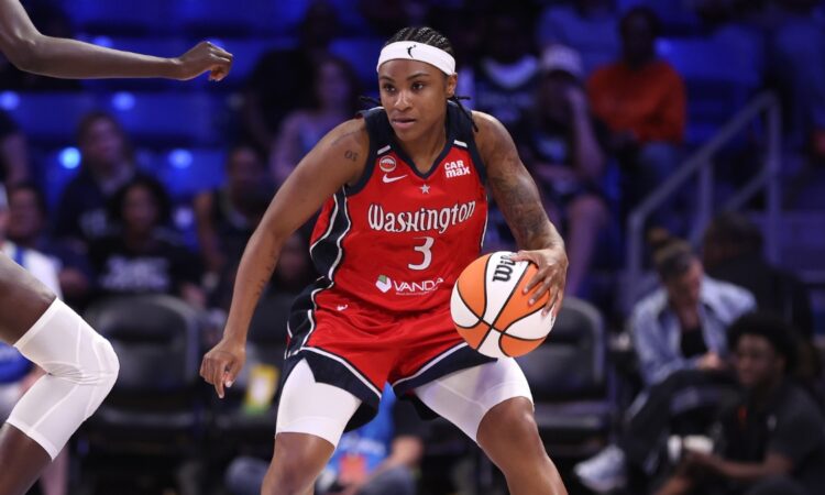 Washington Mystics guard Rori Harmon driving the ball along the perimeter as Dallas Wings forward Awak Kuier uses her length to close down the lane defensively.