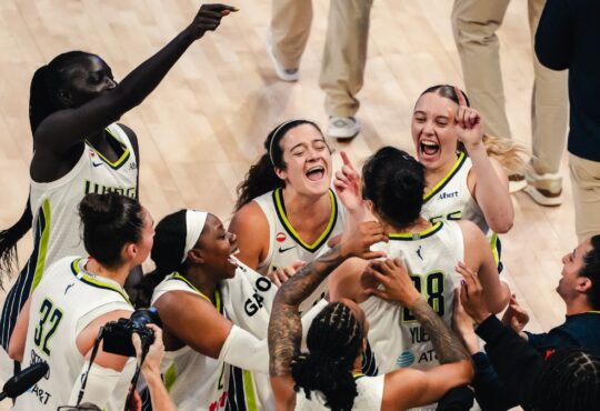 Dallas Wings players swarm Li Yueru and Aziaha James to celebrate a 93-92 comeback win over the Chicago Sky, with Paige Bueckers and Jessica Shepard joining the mob.
