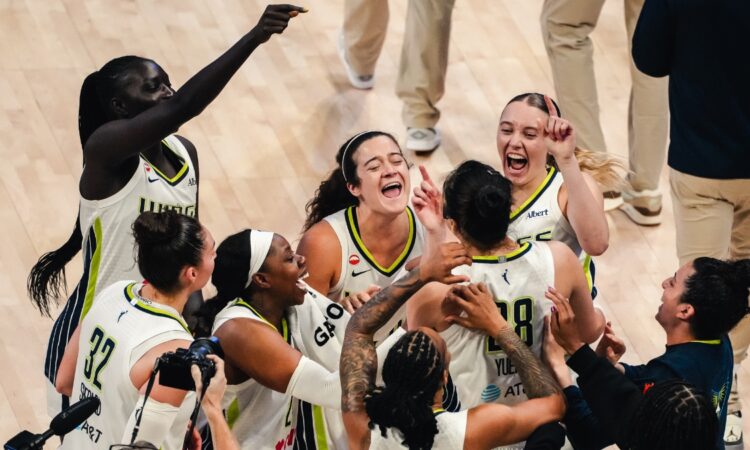 Dallas Wings players swarm Li Yueru and Aziaha James to celebrate a 93-92 comeback win over the Chicago Sky, with Paige Bueckers and Jessica Shepard joining the mob.