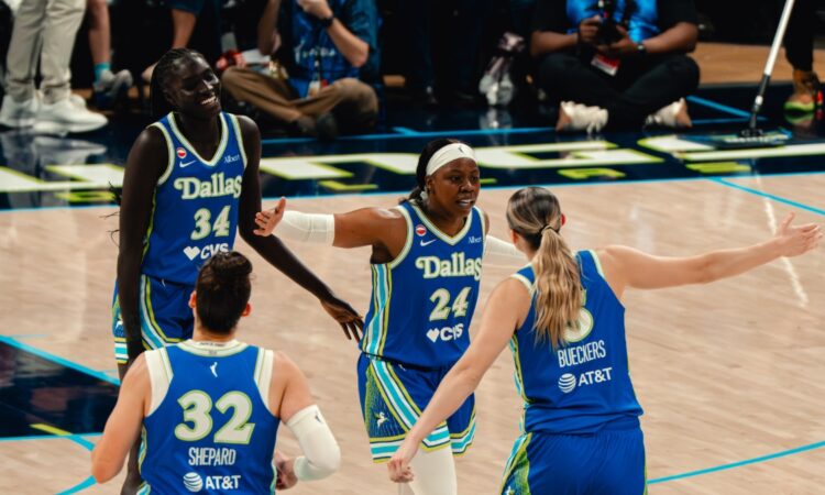 Dallas Wings players Awak Kuier, Jessica Shepard, Arike Ogunbowale, and Paige Bueckers celebrate during a WNBA game against the Las Vegas Aces at College Park Center in Arlington, Texas, on June 15, 2026.