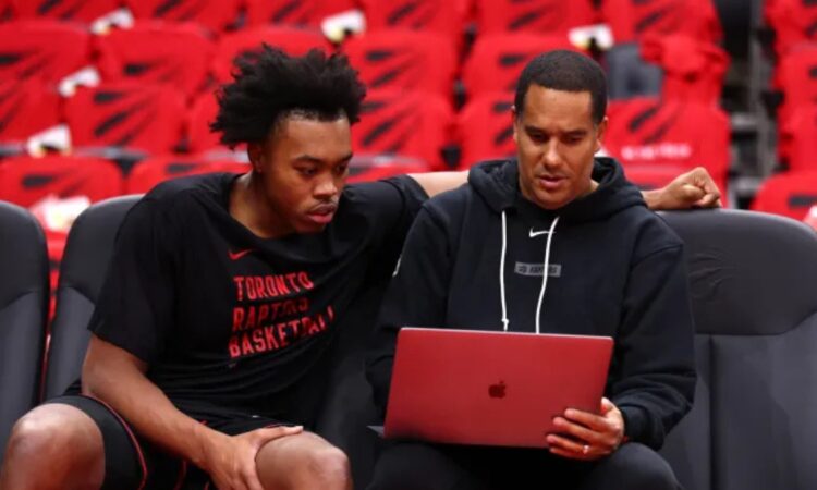 Toronto Raptors assistant coach and Mavericks head coaching candidate Jama Mahlalela reviews film on a laptop with forward Scottie Barnes on the bench