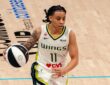 Dallas Wings guard JJ Quinerly dribbles up the court in a white No. 11 home jersey during a game against the Phoenix Mercury.