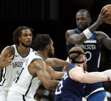 Julius Randle #30 of the Minnesota Timberwolves looks to pass against Cam Thomas #24 and Nic Claxton #33 of the Brooklyn Nets at Barclays Center.