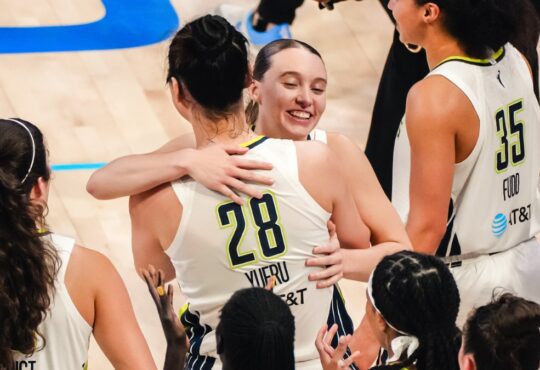 Dallas Wings guard Paige Bueckers embraces center Li Yueru as teammates celebrate a 2026 WNBA win over the Chicago Sky