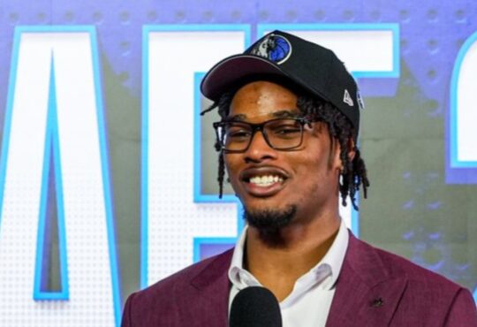 Morez Johnson Jr. smiles in a Dallas Mavericks cap and maroon suit while speaking on stage after being drafted No. 9 in the 2026 NBA Draft