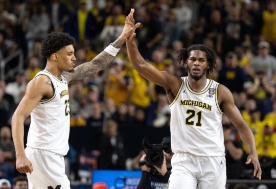 Morez Johnson Jr. in a white Michigan No. 21 jersey high-fives a teammate during the 2026 Final Four