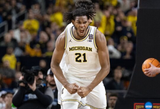 Morez Johnson Jr. flexes and celebrates in a white Michigan No. 21 jersey during the 2026 NCAA national championship game against UConn